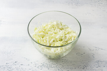 Chopped white cabbage in a glass bowl. Cooking delicious homemade salad. Step-by-step instruction. Step 1.