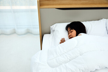 Fototapeta na wymiar Close up Asian woman sleeping on white bed in the bedroom with sweet dreams and enjoys good rest at home with copy space