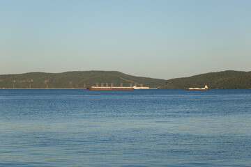 The concept of a healthy lifestyle. View of the river, along which wooded mountains stretch. The sun's rays fall on the mountains at sunset. Sunset. Landscape.