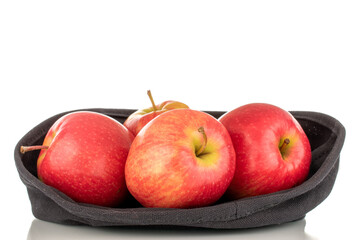 Four juicy red apples with a black linen basket, close-up, isolated on a white background.