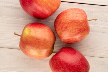 Four juicy red apples on a wooden table, close-up, top view.