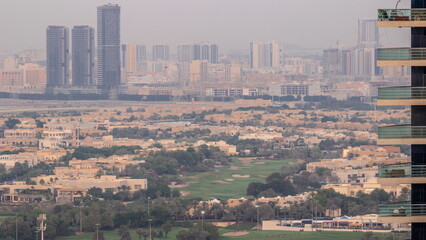 Aerial view of housing development promenade with JLT district skyscrapers and artificial lake with a park timelapse.