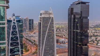 Tall residential buildings at JLT aerial day to night timelapse, part of the Dubai multi commodities centre mixed-use district.