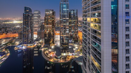 Tall residential buildings at JLT aerial day to night timelapse, part of the Dubai multi commodities centre mixed-use district.