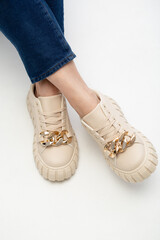 Modern female sneakers. Beige fаemale shoes on feet. Sneakers closeup om white