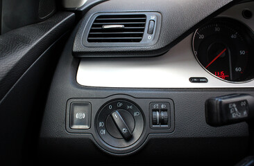 Fototapeta na wymiar Car interior with light switch, automatic control of switching on and off the car light and Air ventilation grille with power regulator. Dashboard for switching on the headlights and fog lights.