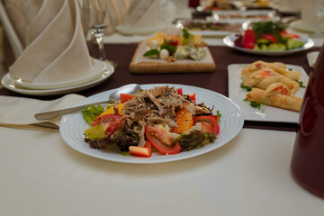 Festive table with appetizers. Meat and vegetable salad, pancakes with caviar and microgreen. Empty glasses, plates for guests