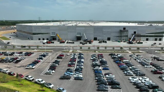 Huge Giga Texas building under construction. Employee parking at location in June 2022. Aerial view of manufacturing plant for electric vehicles by Elon Musk.