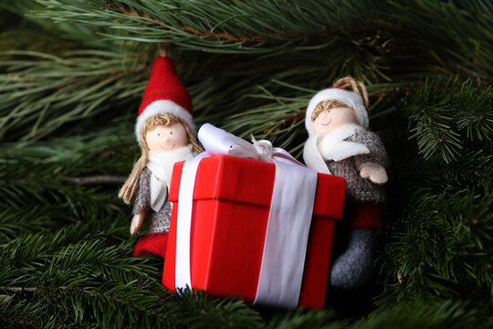christmas elves - a boy and a girl with christmas gift on fur tree brunches. Winter concept. Horizontal image