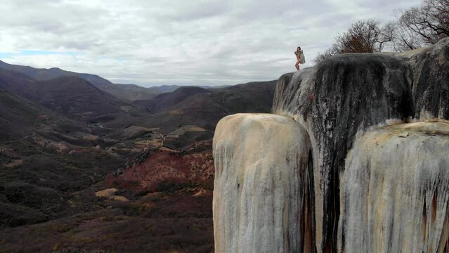 Aerial Drone Shot Asian Girl Dancing on the Edge of Natural Petrified Waterfall Hierve el Agua in Mexico, Oaxaca. 