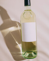 Сlose-up of a bottle of white wine with a beautiful glare from the sun on a white background.Blank white label mock up,empty sticker. Alcohol bottle mockup presentation ready for logo design.