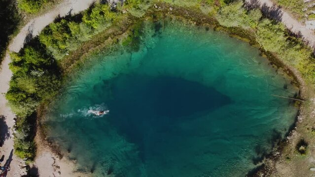 Aerial view of an amazing lake in Cetina river, Croatia where a man swims. Nautral karst lake in Croatia with clear blue water on a sunny day. 