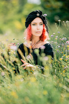 Woman in black dress with red hair in wildflowers pagan image