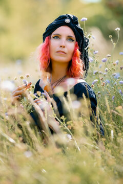 Woman in black dress with red hair in wildflowers pagan image