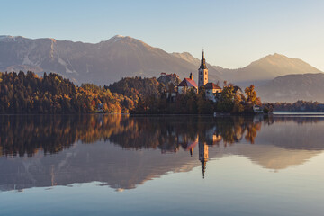 Fototapeta na wymiar Lake Bled at Sunrise. Church, castle and the mountains are basking in the morning sun