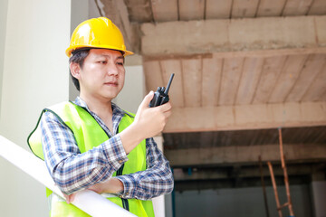 building contractor wearing a yellow helmet Carrying a radio to coordinate with co-workers on the project site. Architectural Concepts, Building Construction. copy space