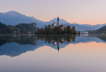 Lake Bled at Sunrise. Church, castle and the mountains are basking in the morning sun