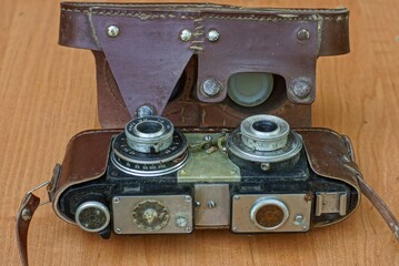 a very old classic iron film camera in an old brown leather case for stereoscopic shots