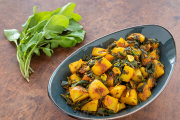 Spicy potatoes with arugula dish (Aloo Arugula). Homemade Indian cuisine meal.