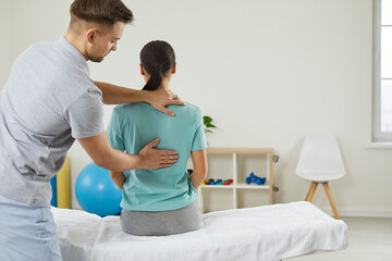 Fototapeta Licensed osteopath examining young woman in modern hospital office. Chiropractor helping female patient with scoliosis, low back pain or other spine problems. obraz