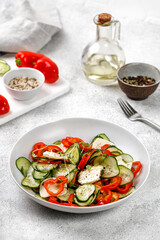 Mix organic salad with sliced cucumbers, feta cheese, paprika in a plate. Fresh green snack. Keto diet. Vegetarian food.