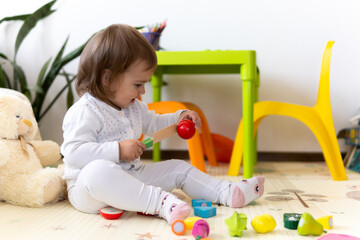 happy funny kid curly baby girl with educational toy blocks flowers. Children play at day care or preschool. Mess in kids room. Toddler build tower in kindergarten. Child playing with colorful toys