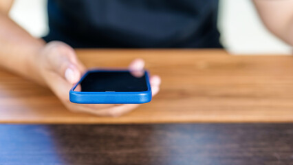 Closeup woman using a smartphone on the wood table