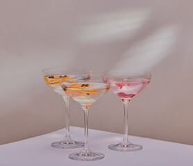 Mixed cocktails on a white surface, with sun light patterns on background.