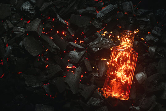 Bottle of whiskey on the blazing charcoals background. Top view.