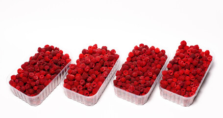 Ripe red fragrant raspberries collected in a farm in a transparent container for sale.