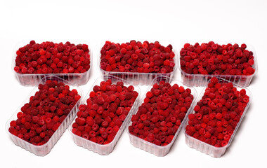 Ripe red fragrant raspberries collected in a farm in a transparent container for sale.