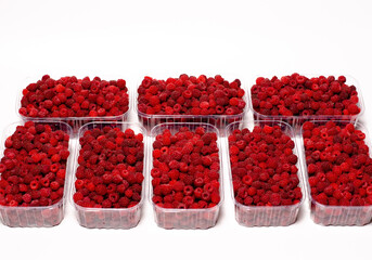 Ripe red fragrant raspberries collected in a farm in a transparent container for sale.
