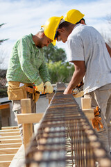 bricklayers with yellow helmet and protective glasses building an iron beam for reinforced concrete - PHOTO SESSION: WORK IN CONSTRUCTION