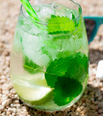 Image of a marine still life. A glass of majito on the sand with headphones and glasses. Relaxation