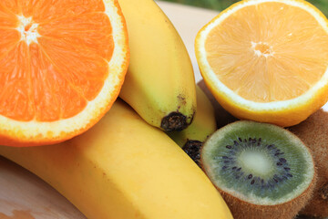Group of ripe fruits from banana, orange, lemon and kiwi, close photo. Composition of fruits, some cut in half