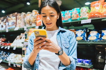 Happy young woman wearing earphones using smartphone
