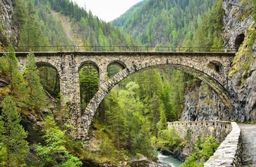Fototapeta na wymiar Viaduct in Davos Monstein. Landwasser river flows through the canyon. hike along the river in the valley to filisur. Old