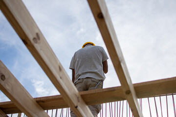 male builder performs work on the roof, fastens corrugated sheets