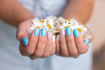 Obraz na płótnie Canvas Female hands with summer manicure nails, decorated with camomile flowers