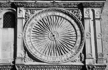 Ancient astronomical clock in Sun shape on the facade of famous Chartres cathedral (France). Aged photo. Black and white.