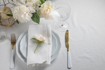 romance table setting with peony flowers on white tablecloth with golden cutlery. Copy space