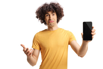 Confused young man holding a smartphone and gesturing with hand