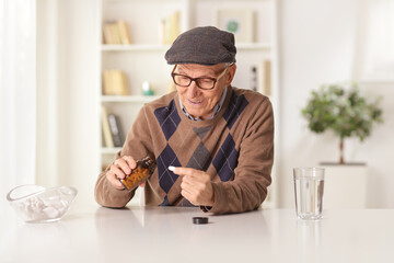 Pensioner sitting at home and taking a pill