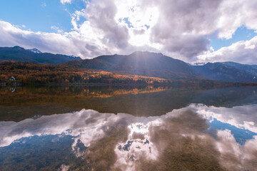 Autumn landscape by the lake Bohinj in Julian Alps. Fascinating reflectins in the lake on a cloudy day.