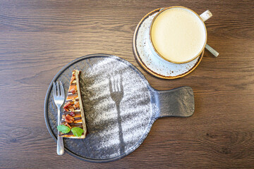 a cup of coffee with milk and cheesecake with nuts. cappuccino with dessert