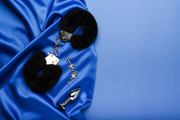 black fluffy handcuffs and sex toy on a blue background