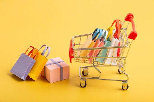 Trolley cart with colorful paper shopping bags isolated. Creative idea for shopping online, sale, supermarket, discount promotion and summer sale concept.