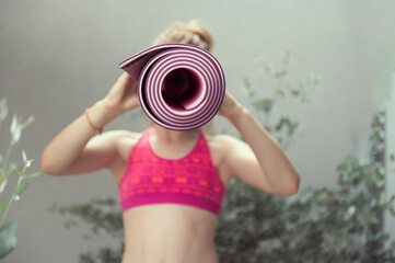 Teen girl is fooling around and hiding behind her yoga mat