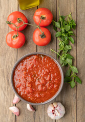 Tomato sauce, tomatoes, garlic, olive oil and herbs over wood table
