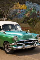 Obraz na płótnie Canvas Old american car with colourful mural wall from Vinales, Cuba